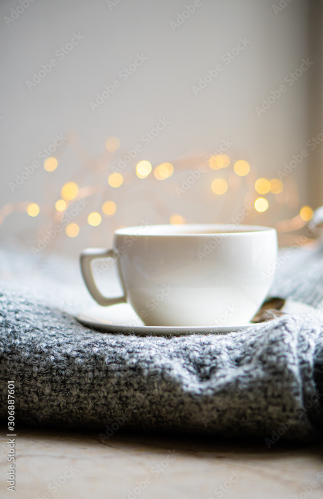 Cup of coffee with milk on cozy knitted winter blanket