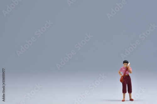 miniatuur woman standing is talking on a handy