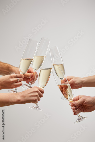 cropped view of men and women toasting champagne glasses with sparkling wine isolated on grey