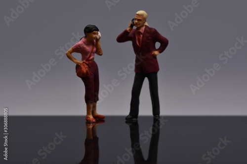 two tiny people talking on a smartphone