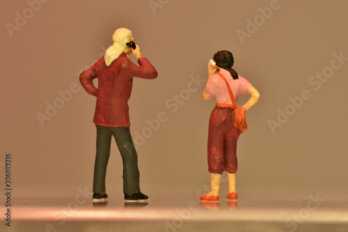 two tiny people talking on a smartphone