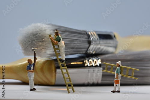 tiny painters are painting. Standing on a ladder, walking around brushes