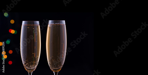 Two glasses with champagne with festive lights on a dark background.