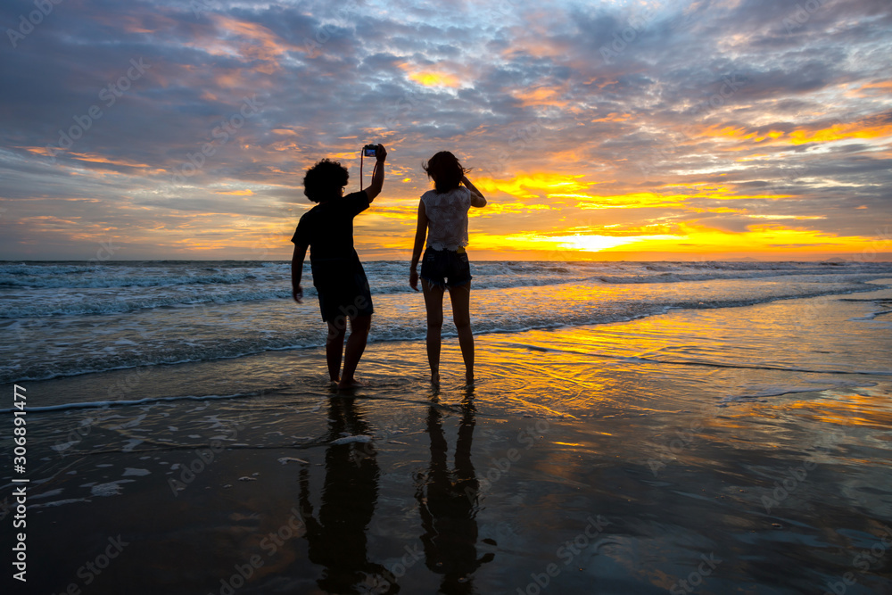 Black silhouettes of couple girl against the sunset on the sea.