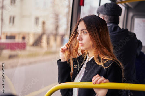 woman rides on a bus and looks out the window. public transport