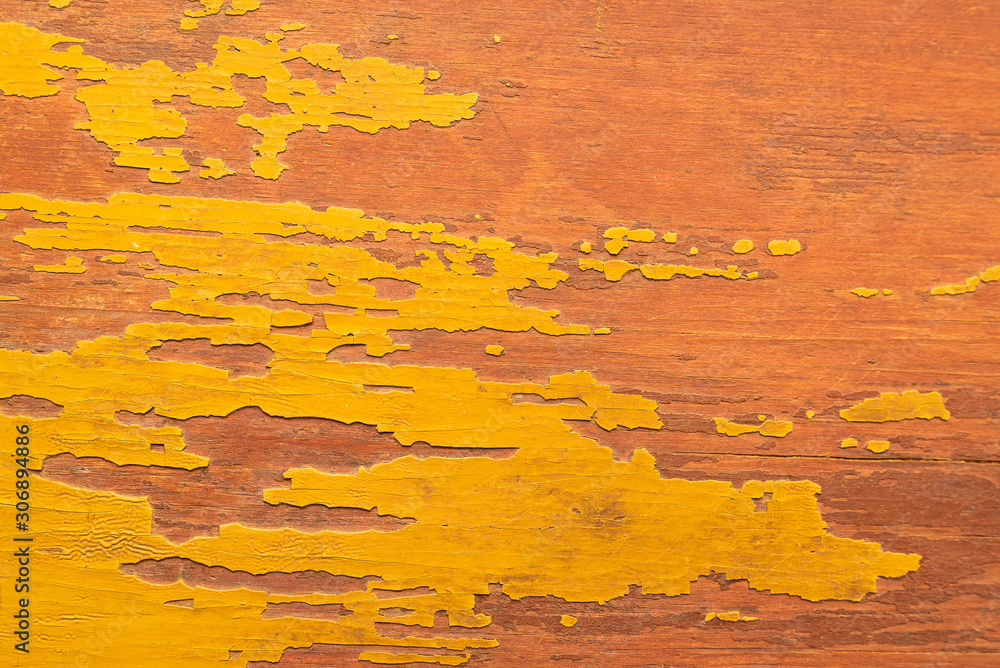Texture of peeling yellow paint on an old wooden surface.
