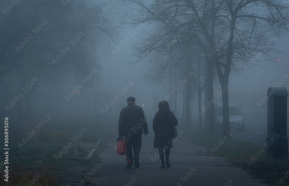 Old couple walking on street a foggy day