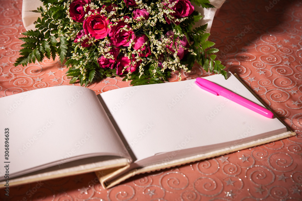Fototapeta premium Wedding album, blank page, guest list, to do list.still life photography concept by memory and notebook.Red rose flower and Notepad book.Notebook and asters on canvas background.