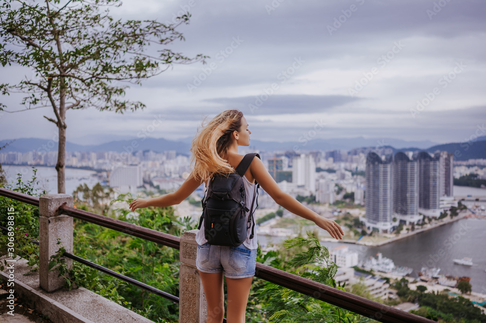 Traveler blonde backpacker woman walking overlooking the downtown. Travel adventure in China, Tourist beautiful destination Asia, Summer holiday vacation trip. Freedom and happy people concept