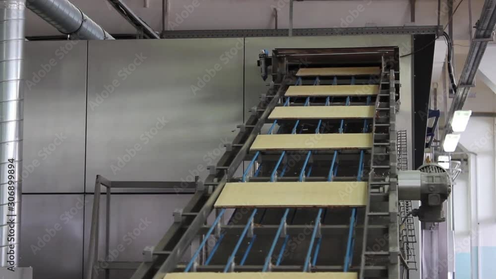 Glued cakes for chocolate wafers move from top to bottom along the conveyor belt. Glued cakes for chocolate wafers move from top to bottom along the conveyor belt.