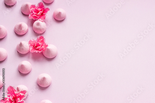 Small meringues and pink flowers on pink paper background. A pattern of small meringues and flowers. Gift for Valentine s Day.