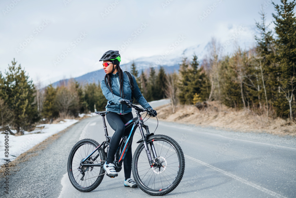 Female mountain biker standing on road outdoors in winter nature. Female mountain biker standing on road outdoors in winter nature.