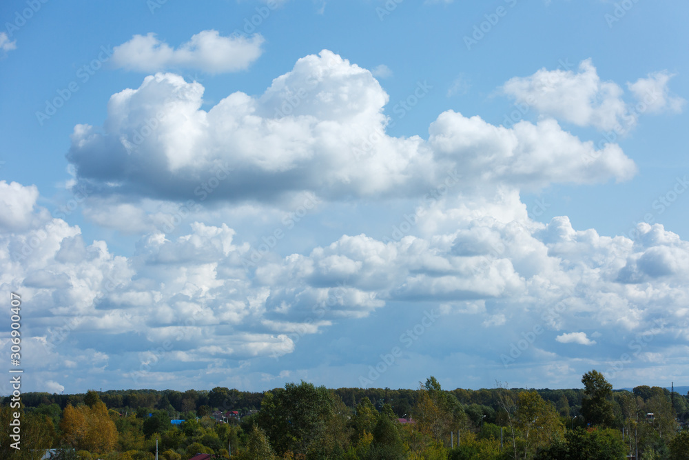 White and thick clouds in a blue sky. Cloudy sky and horizon.