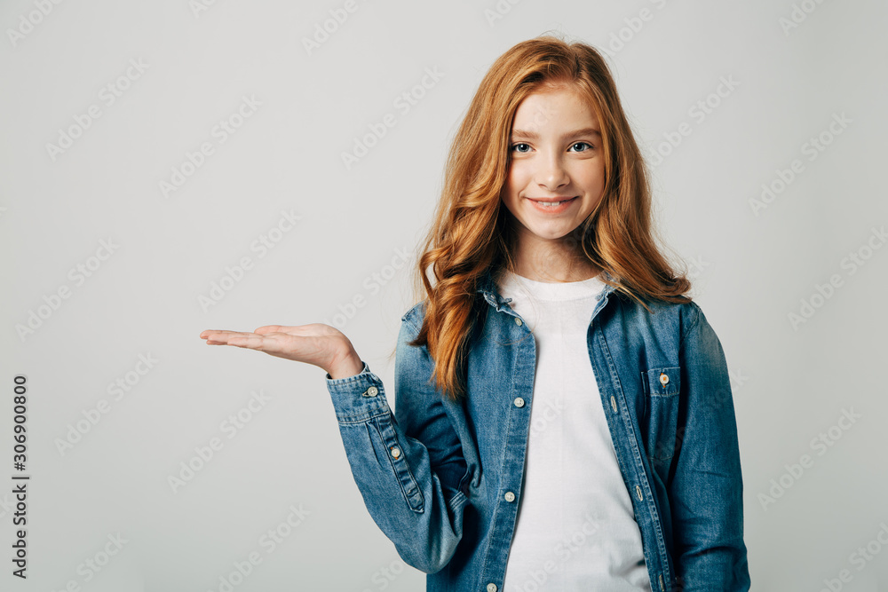 The red-haired girl smiling and points to a place for an inscription. Something on her hand. Isolated The red-haired girl smiling and points to a place for an inscription. Something on her hand. Isolated