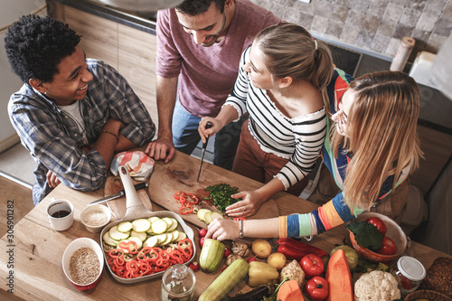 Group of friends preparing vegetarian meal.They preparing food and making fun in the kitchen.	