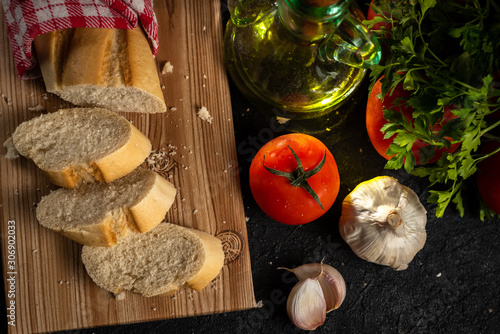 ingredients for preparing bread with tomato and oil, on dark wooden background photo