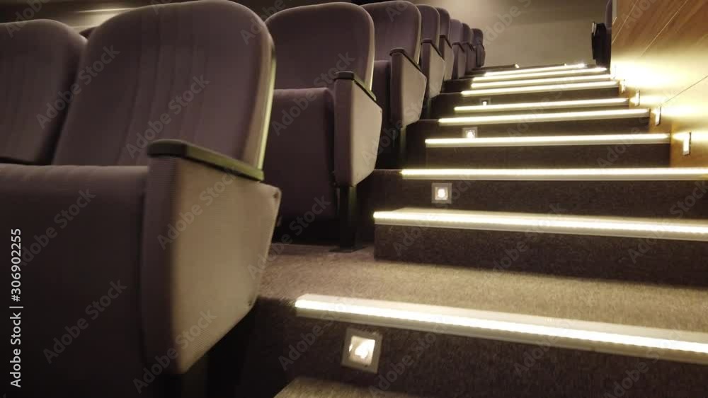 Walking up stairs in empty cinema, theater hall. Rows of seats and ...