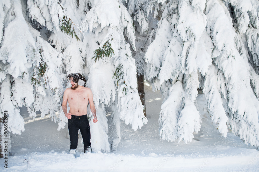 Topless young man outdoors in snow in winter forest, having fun. Topless young man outdoors in snow in winter forest, having fun.