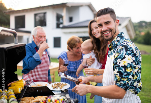 Portrait of multigeneration family outdoors on garden barbecue  grilling.