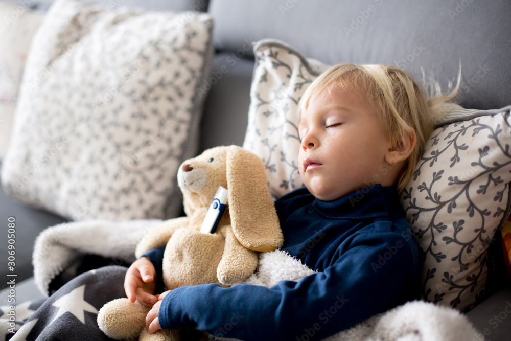 Blond toddler boy, sleeping on the couch in living room, lying down with fever Blond toddler boy, sleeping on the couch in living room, lying down with fever