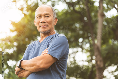 Asian Senior man in blue shirt smiling with arms crossed before exercising.