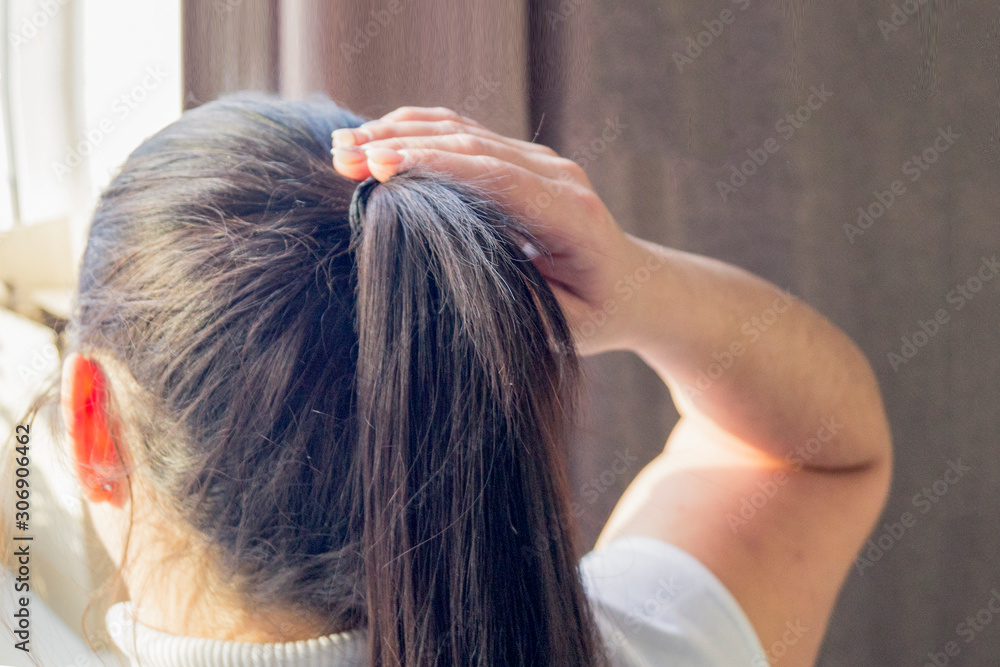 Naklejka premium a young girl combs her hair. brunette