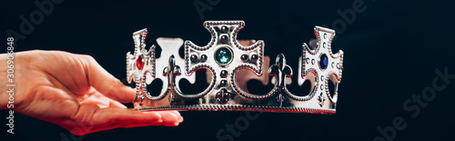 Fotografie cropped view of woman holding silver crown with gemstones, isolated on black, pa