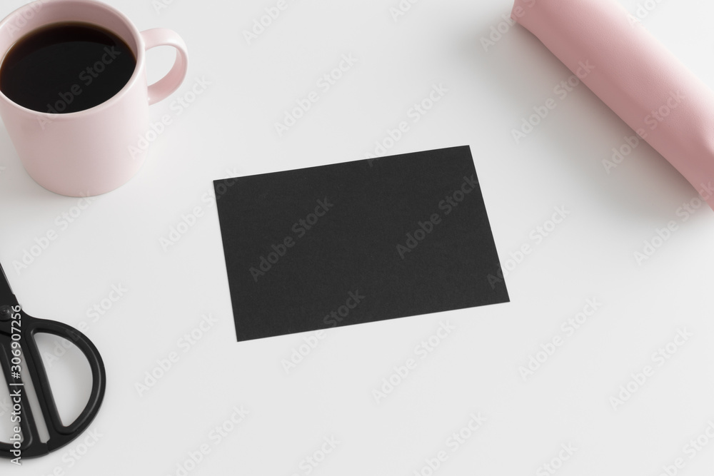 Top view of a black card mockup with workspace accessories and a cup of coffee on a white table. Top view of a black card mockup with workspace accessories and a cup of coffee on a white table.