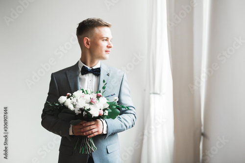 Happy handsome smiling groom posing with boutonniere