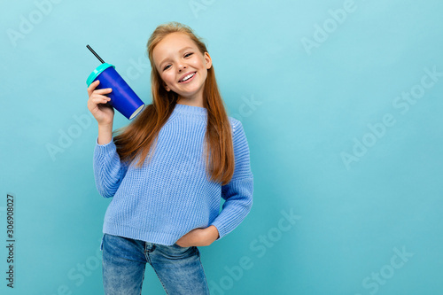 attractive european girl holding a glass in her hands on a light blue background