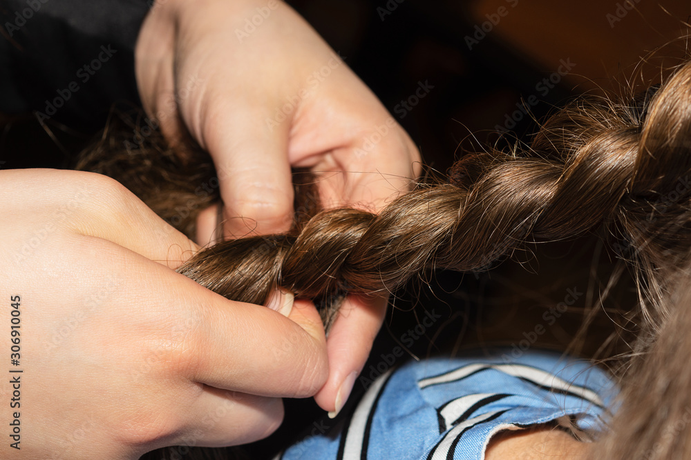 Obraz premium The woman plaits a braid from the hair. Close up.