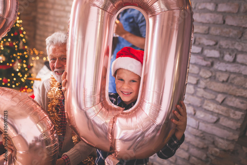 Little boy and his grandfather holding giant number shaped balloons for Christmas