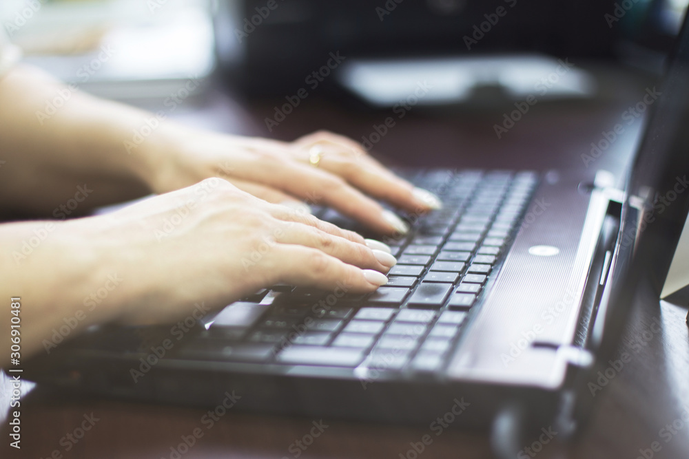 girl in the office is typing on a laptop. girl at work. girl hands on keyboard close girl in the office is typing on a laptop. girl at work. girl hands on keyboard close