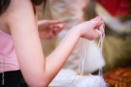 bind holy thread with hand in thai rite.The bride's hands are tied with thread from the older culture in Thailand.