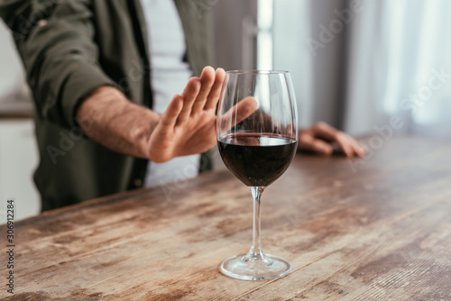 Cropped view of man pulling hand to wine glass on table