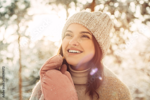 Happy young woman in a knitted hat and mittens in the sun in winter