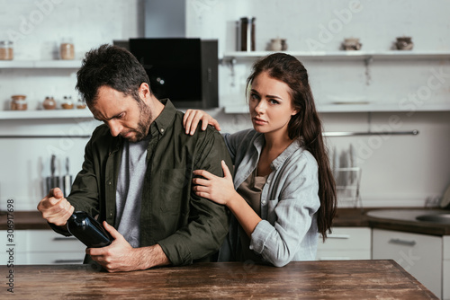 Tablou pe pânză Woman stopping alcohol addicted husband with wine bottle