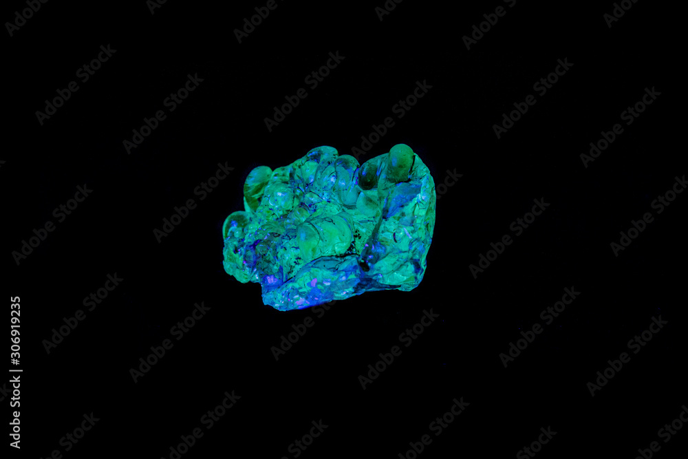 Fototapeta premium macro mineral stone opal under ultraviolet light on a black background
