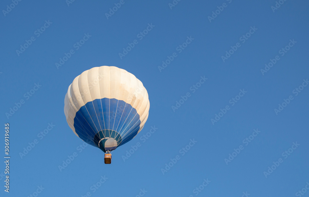 Fototapeta premium Blue and white hot air balloon flying in blue sky