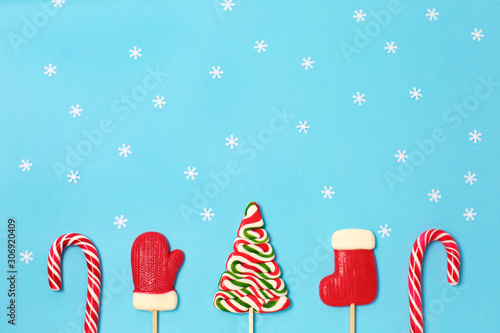 Christmas candies and little white snowflake on blue background.