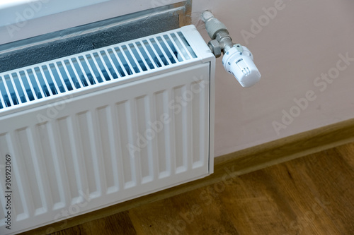 Closeup of heating radiator valve for comfortable temperature regulation on metal radiator on inrerior wall.