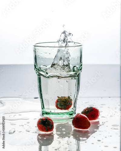 A glass of clean water and fresh red strawberries