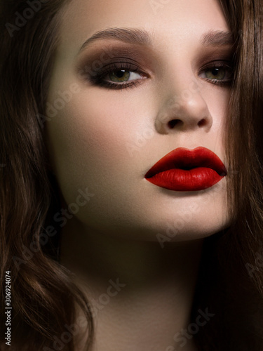 Beautiful brunet model woman face with green eyes and perfect make-up. Portrait of beauty young brunet girl with red lips and smoky eyes  thick eyesbrow . Female face with clear skin close-up.