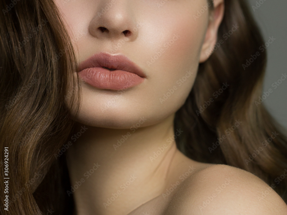 Close-up of woman's lips with fashion natural beige lipstick makeup. Macro sexy pale lipgloss make-up . Gentle pure skin and wavy brunet hair. Cosmetology, Spa, increase in lips Close-up of woman's lips with fashion natural beige lipstick makeup. Macro sexy pale lipgloss make-up . Gentle pure skin and wavy brunet hair. Cosmetology, Spa, increase in lips