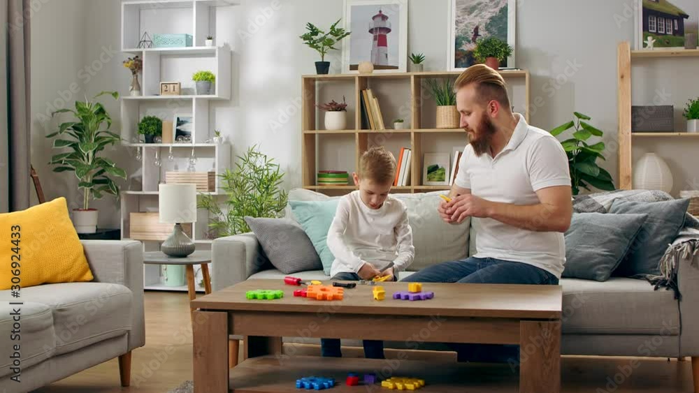 Father and son play with a children s designer in the living room Father and son play with a children s designer in the living room
