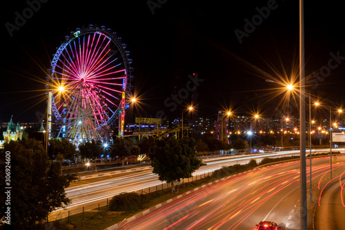 Ferris wheel at night with colored lights photo taken from overpass on the highway