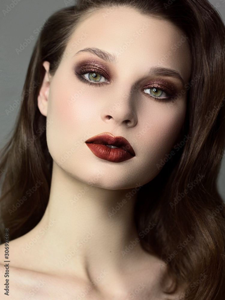 Close up a beauty portrait with beautiful fashionable evening make-up, black smoky eyes and extremely long eyelashes. Brown lipstick on the lips. Cosmetology and spa facial skin care Close up a beauty portrait with beautiful fashionable evening make-up, black smoky eyes and extremely long eyelashes. Brown lipstick on the lips. Cosmetology and spa facial skin care
