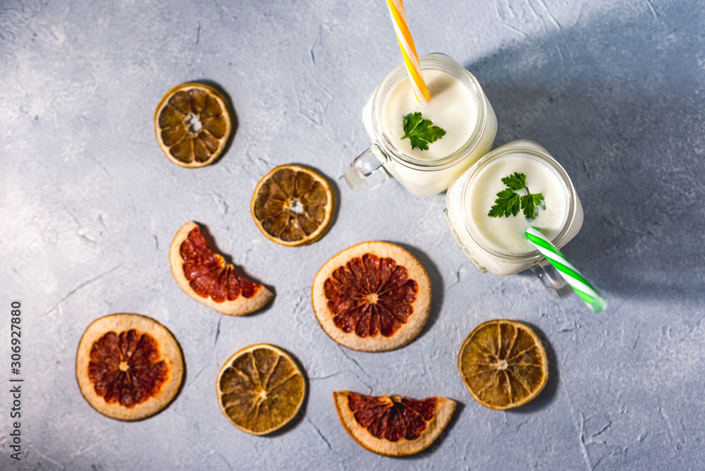 Fototapeta premium simple homemade kefir in a glass with spices and herbs on a gray background, copy space. Probiotic Ayran