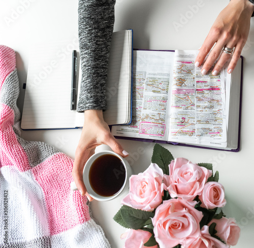 Pink, white, grey Bible flat lay with black tea, pink roses, colorful Bible, pen and a woman’s hand