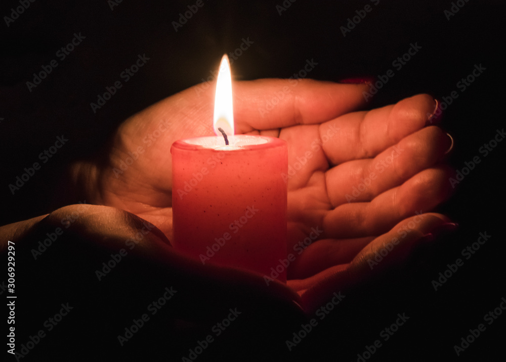 Female hands holding a burning candle in the dark Female hands holding a burning candle in the dark